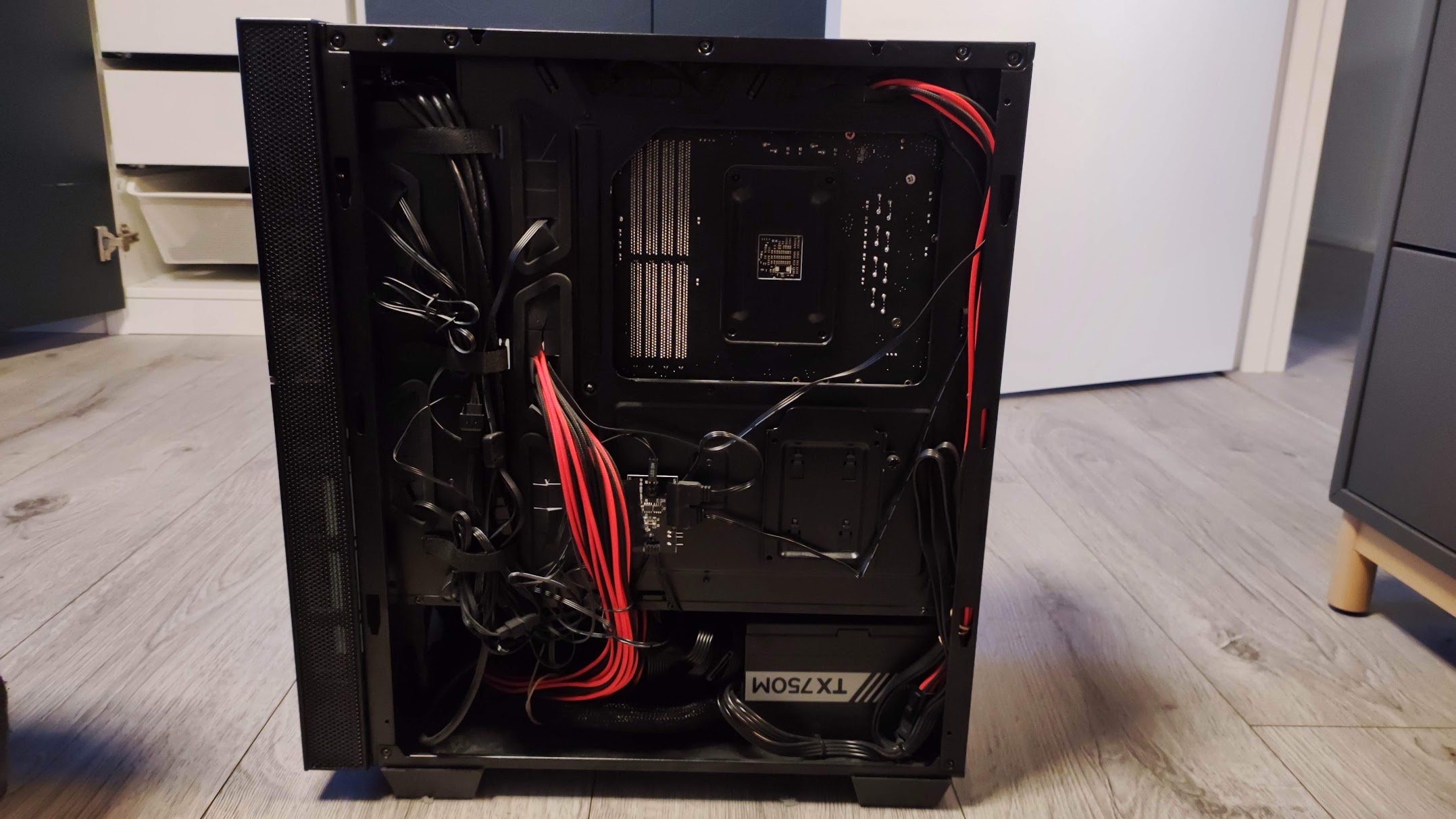The back panel of a PC case showing routed cables