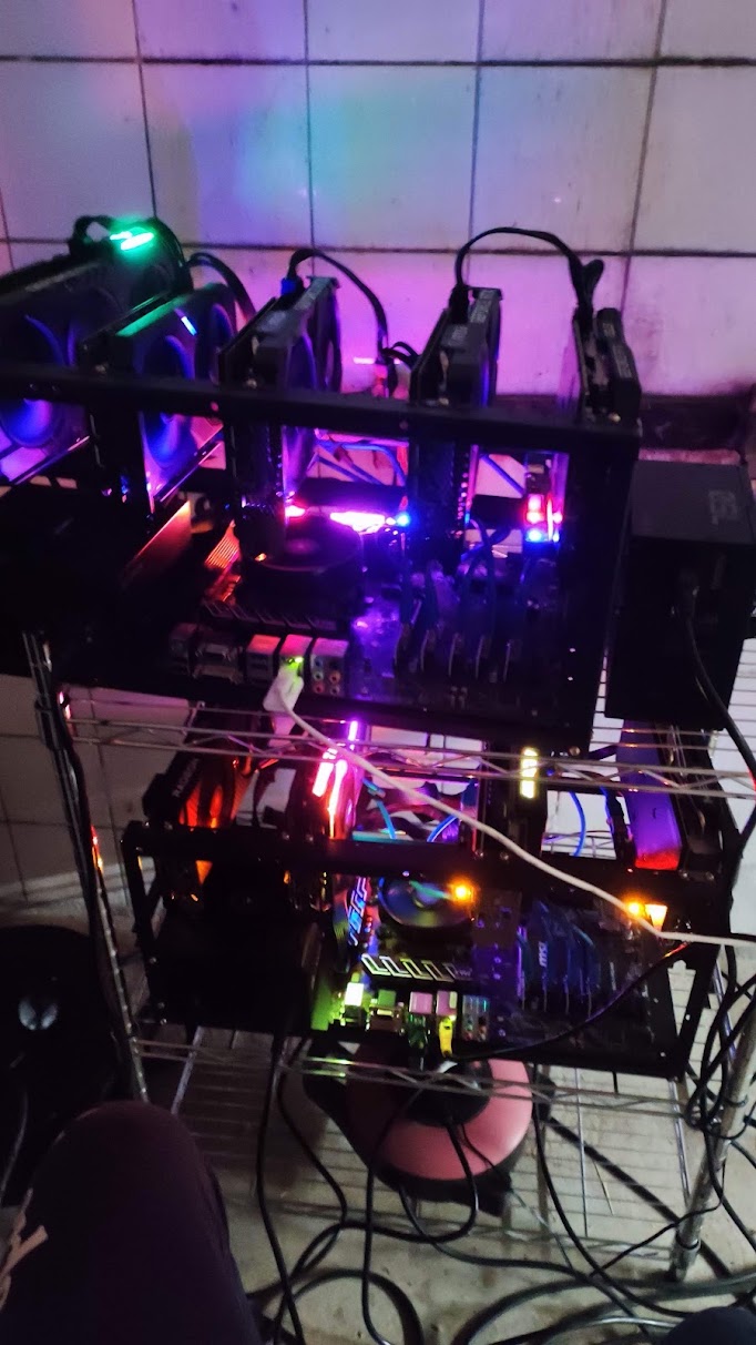 Two RGB-lit mining rigs stacked on open frames in a tiled room